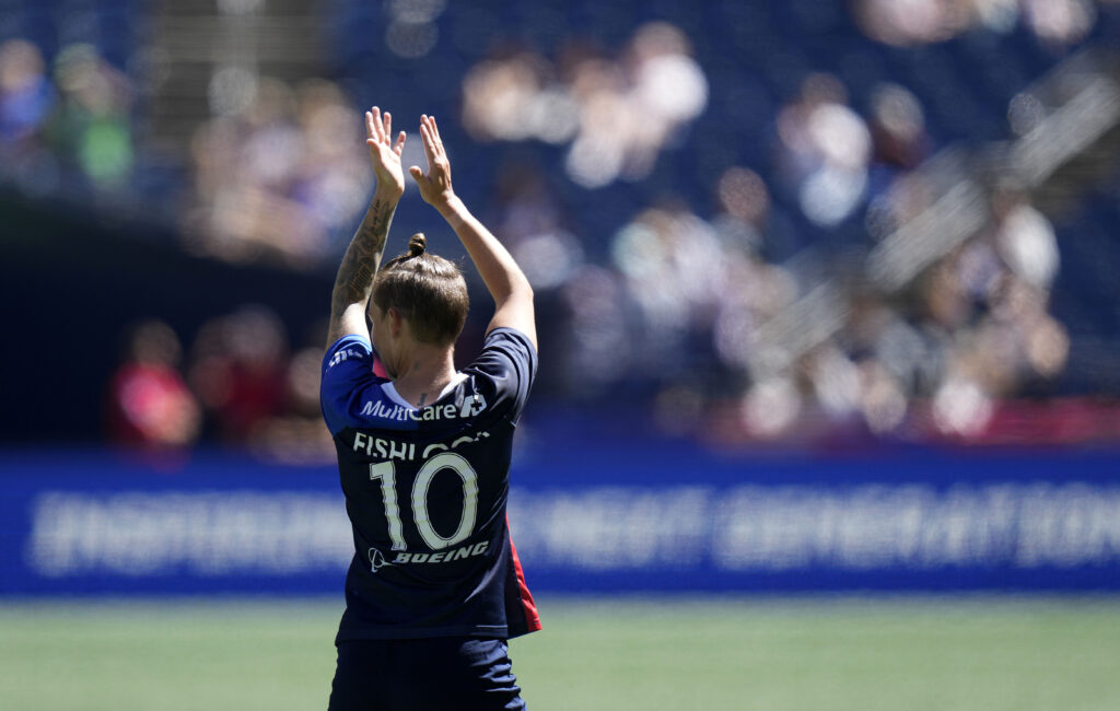 Jess Fishlock claps her hands on the soccer field, wearing Number 10. Photo captured from behind.