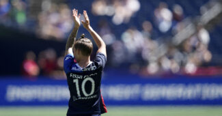 Jess Fishlock claps her hands on the soccer field, wearing Number 10. Photo captured from behind.