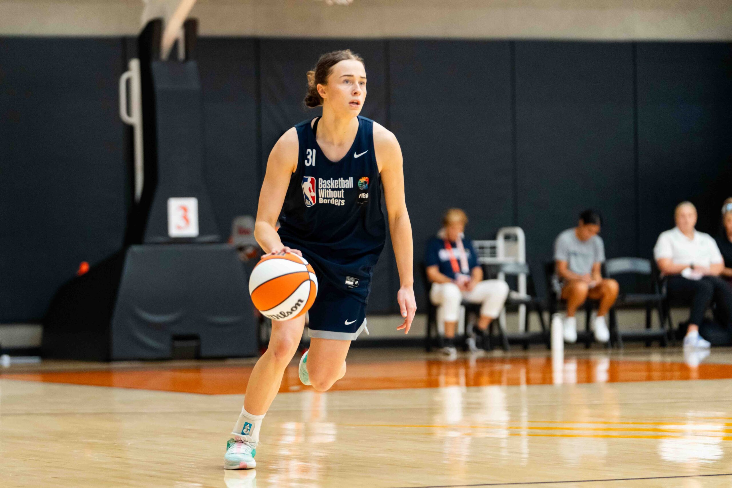 Bonnie Deas runs with the ball, wearing a Basketball Without Borders practice uniform