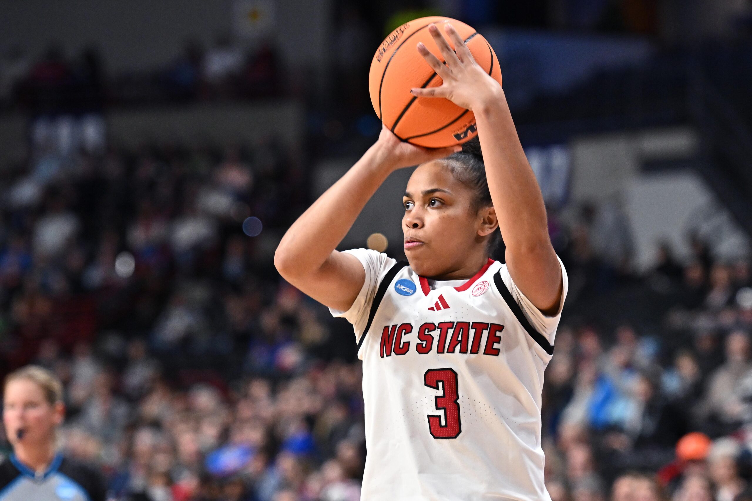 Zamareya Jones cradles the ball with both hands just above her head and looks slightly to her right as she prepares to shoot a jump shot.