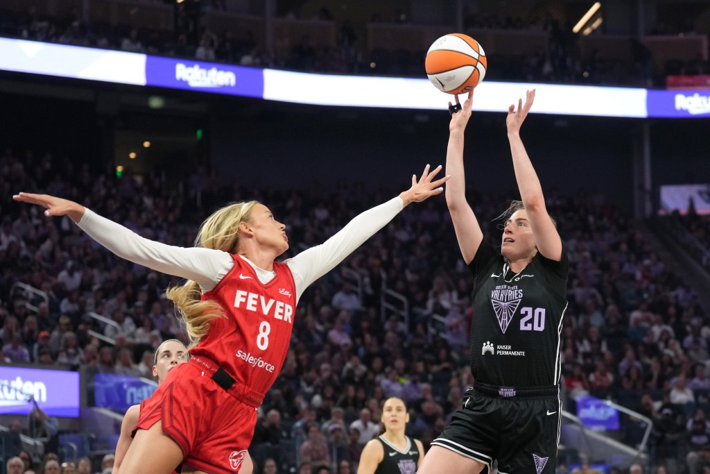 Golden State Valkyries guard Kate Martin shoots against Indiana Fever guard Sophie Cunningham. They are shown from the side, and a packed but out-of-focus crowd is in the background behind them.