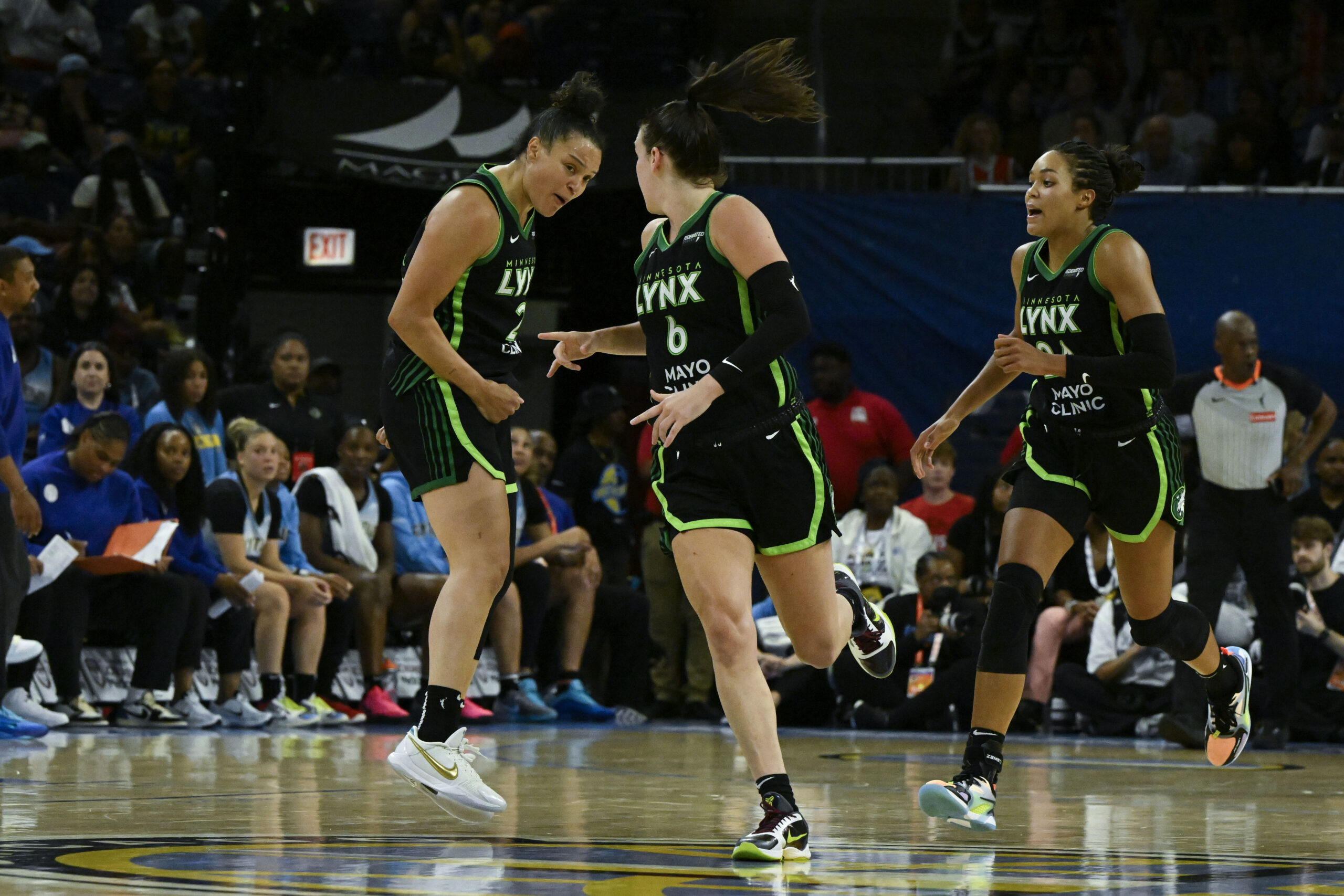 Three member of the Minnesota Lynx run up the floor in their black jerseys with green trim