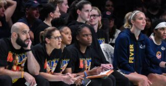 A group of Indiana Fever players and coaches look pensive.