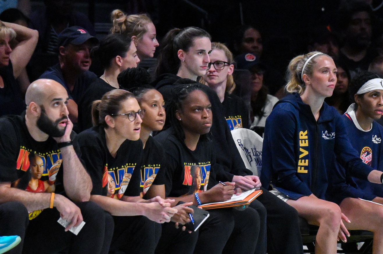 A group of Indiana Fever players and coaches look pensive.
