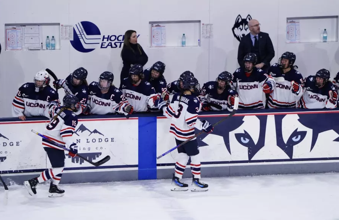UConn women's hockey celebrates with a high five line at their bench.