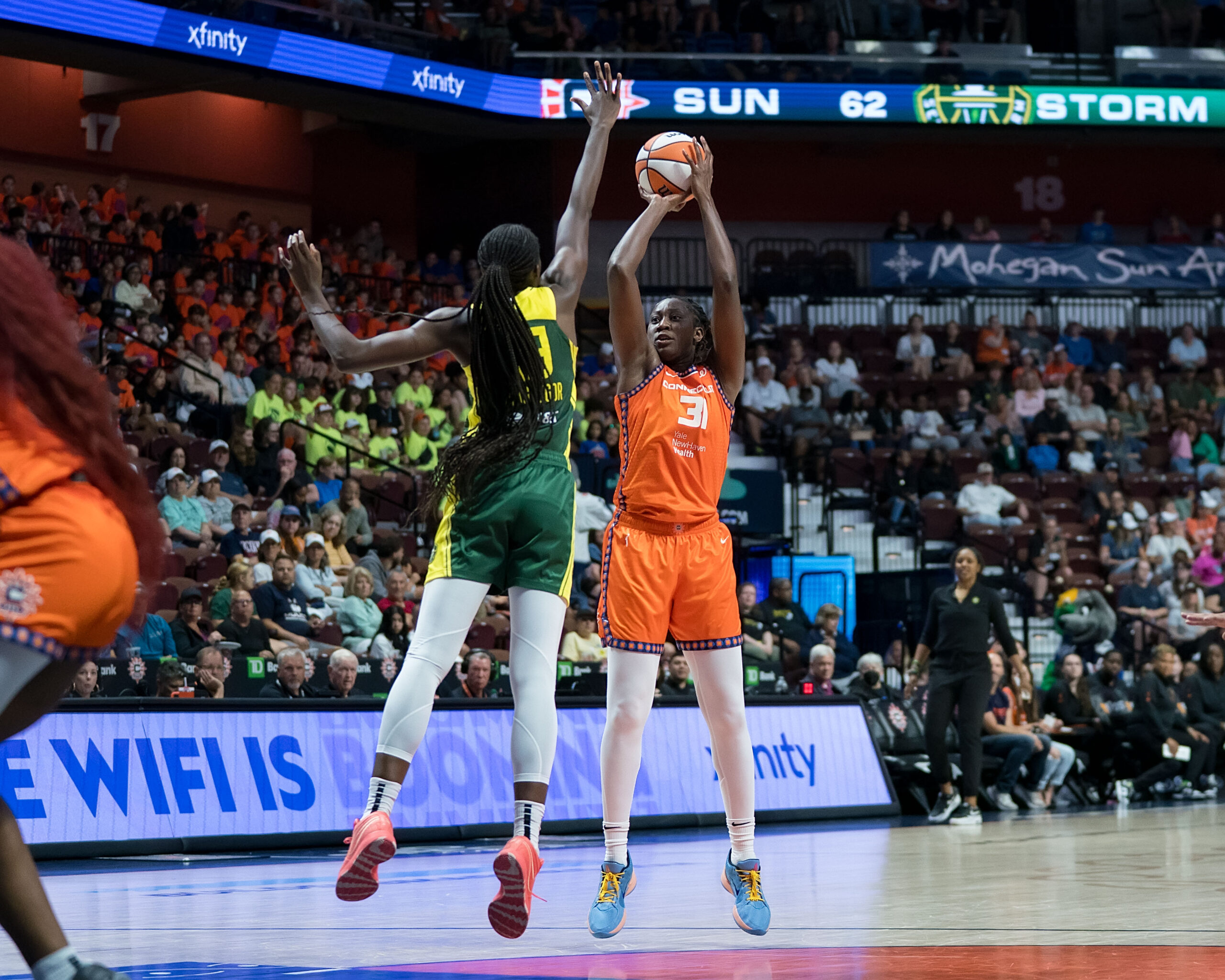 Tina Charles shoots a deep two while Ezi Magbegor flies out with her right hand extended as far as possible to block the shot.