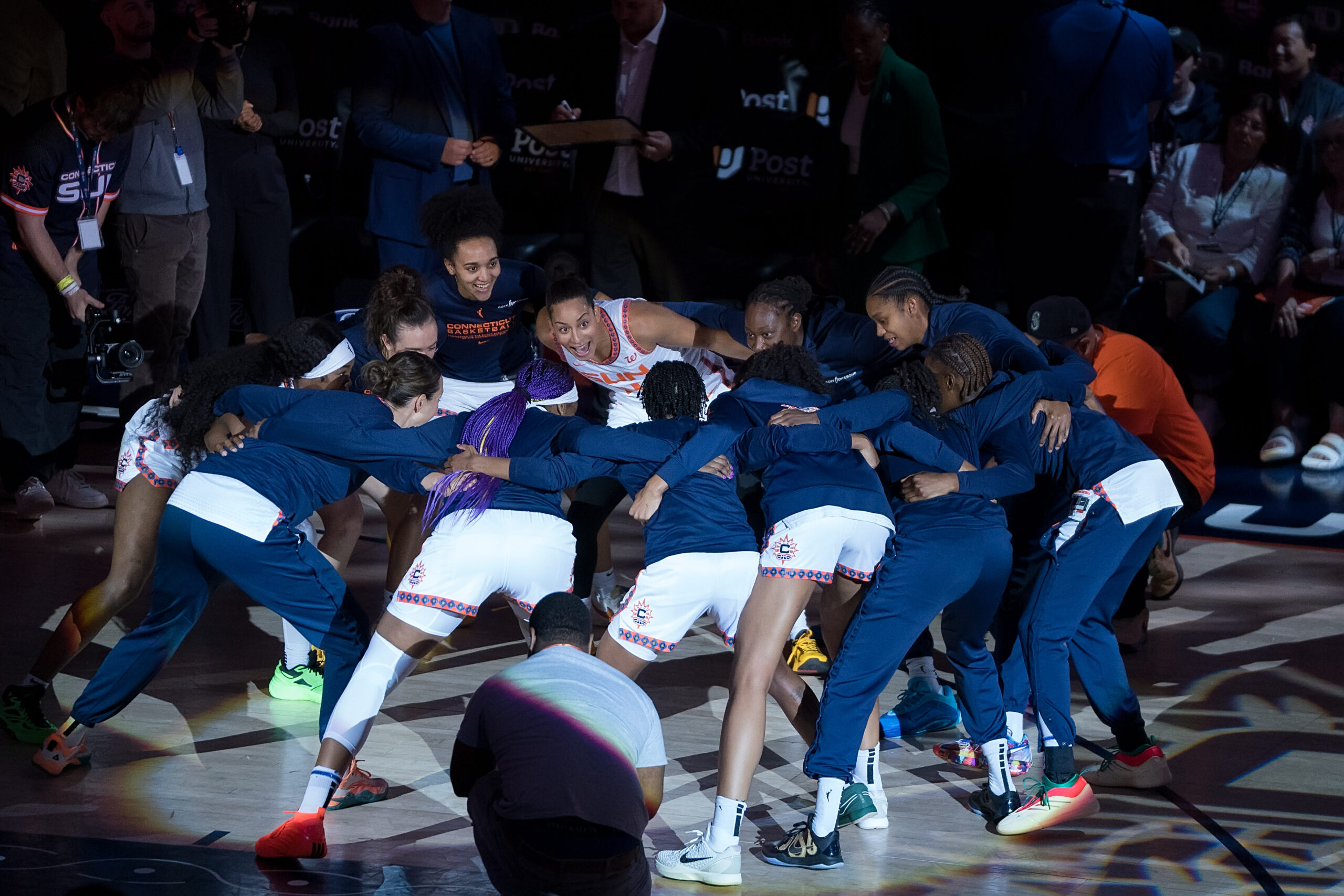 Members of the Connecticut Sun stand in a huddle as they sway back and forth before a game against the Indiana Fever.