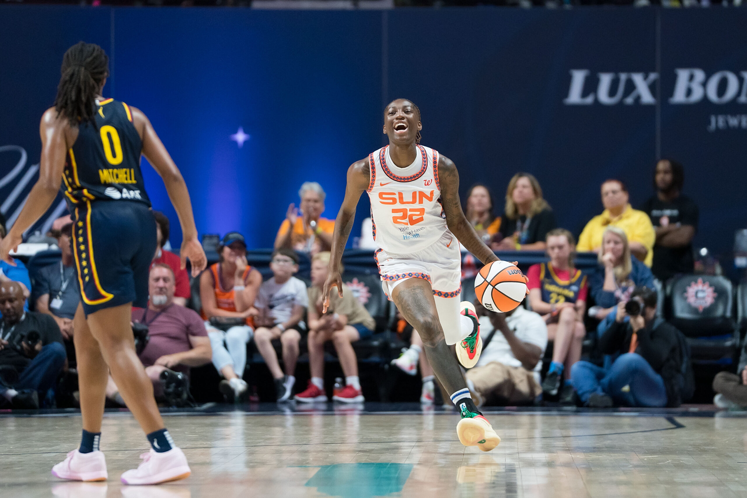 Connecticut Sun guard Saniya Rivers dribbles the ball up the court while smiling.