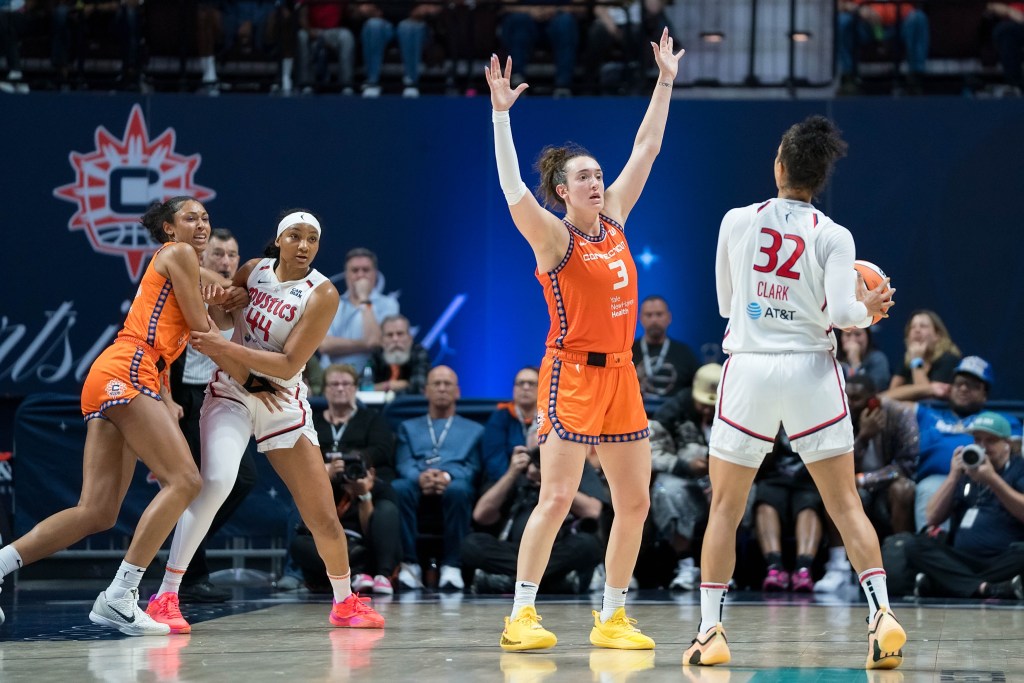 Washington Mystics forward Alysha Clark holds the ball with both hands on the perimeter as teammate Kiki Iriafen battles for position in the post.