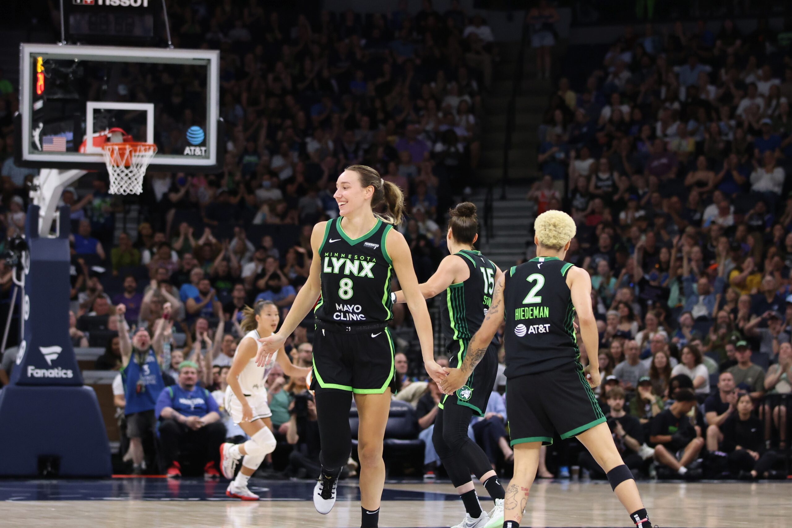 Three players on the Lynx high five each other on the court during a game