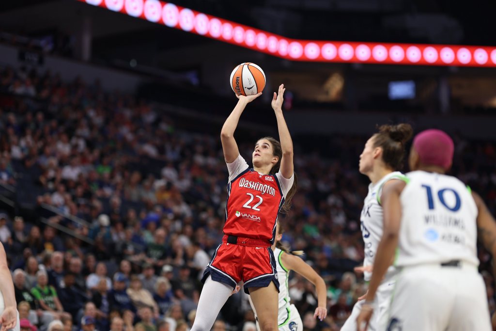 Washington Mystics guard Sonia Citron fades away slightly as she takes an open jump shot. One Minnesota Lynx defender is behind her and two are visible off to one side, but none are close enough to contest her shot.