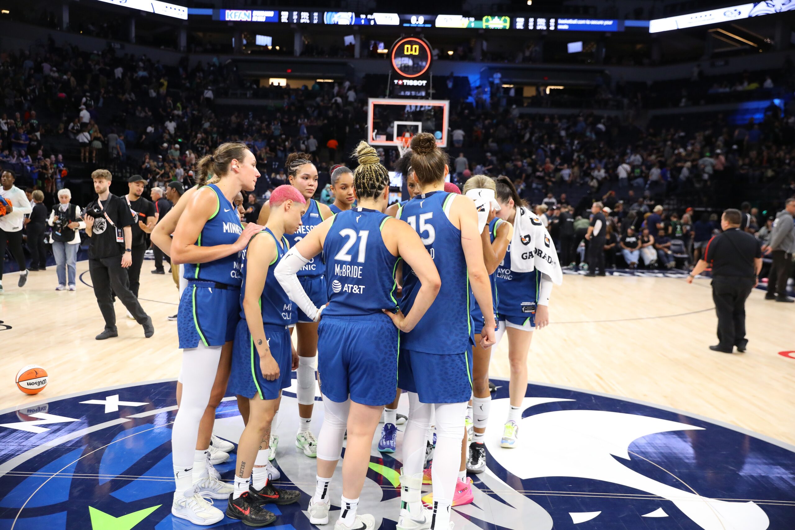 Basketball players all dressed in blue huddle at half court