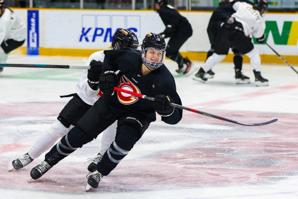 Jessica Adolfsson smiling as she skates besides a teammate at an Ottawa Charge practice