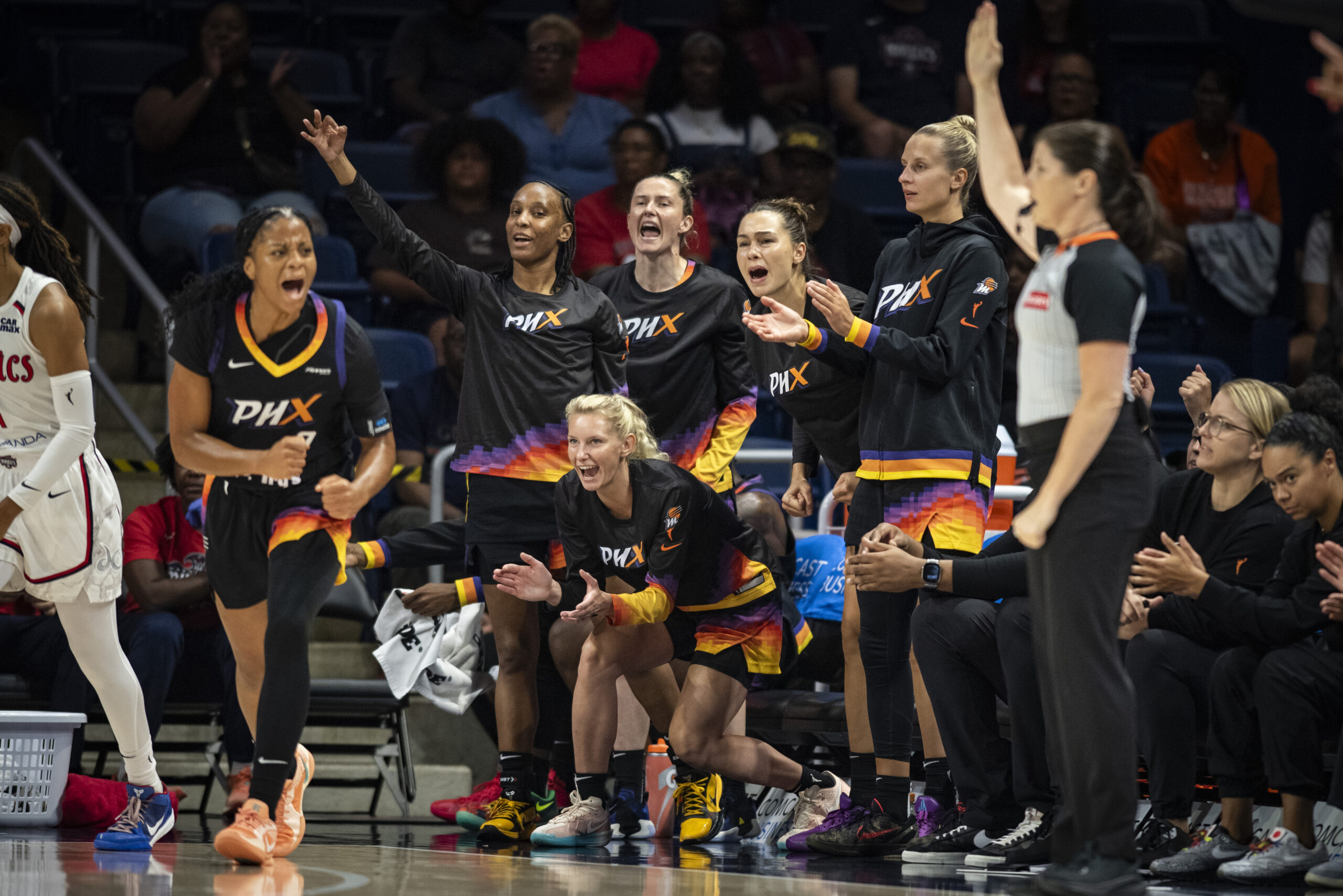 Monique Akoa Makani celebrates making a 3-pointer while teammates celebrate behind her.