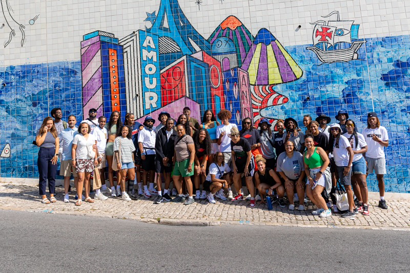 Howard women's basketball is standing in front of a tiled mural wall in Lisbon, Portugal. which is a strong symbol tied to Portugal’s maritime history.