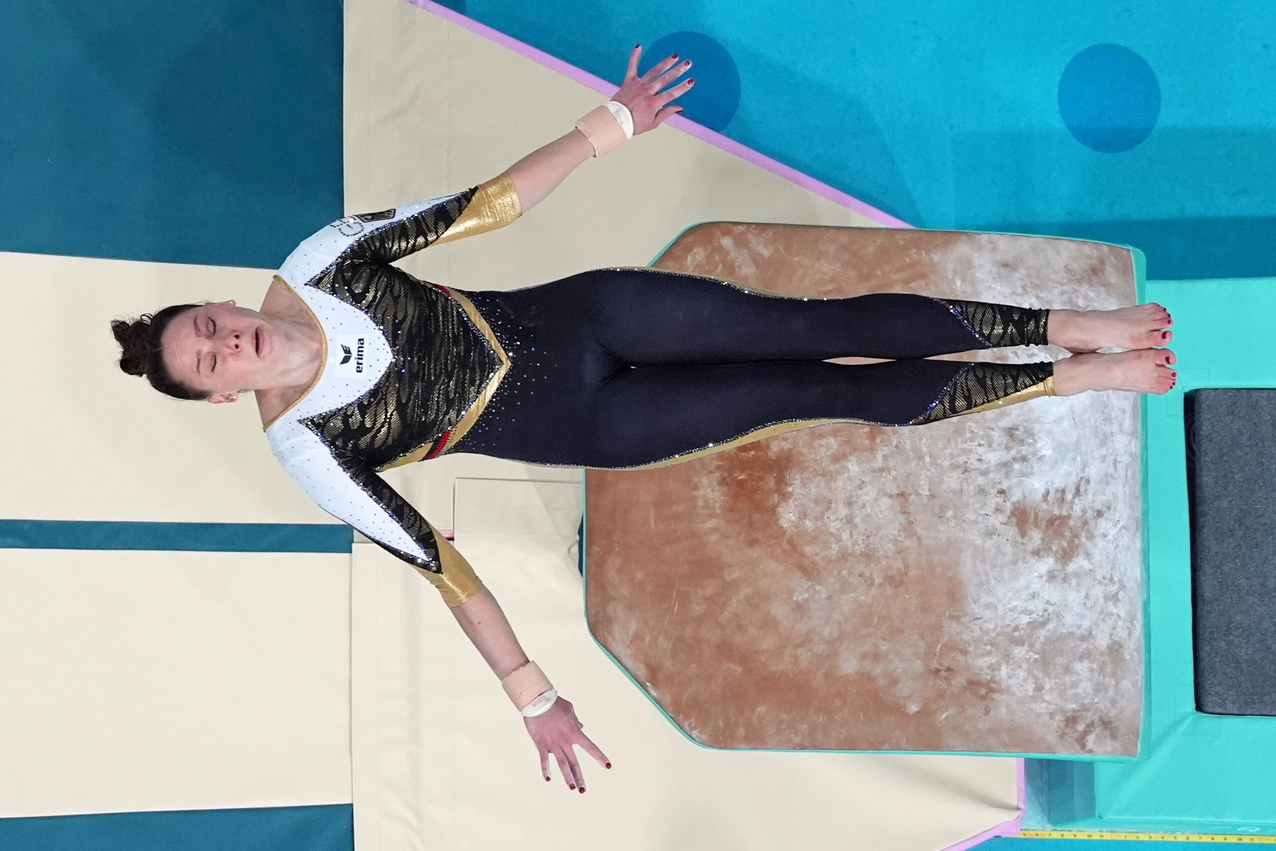A gymnnast in a black and white unitard competes on the vault.