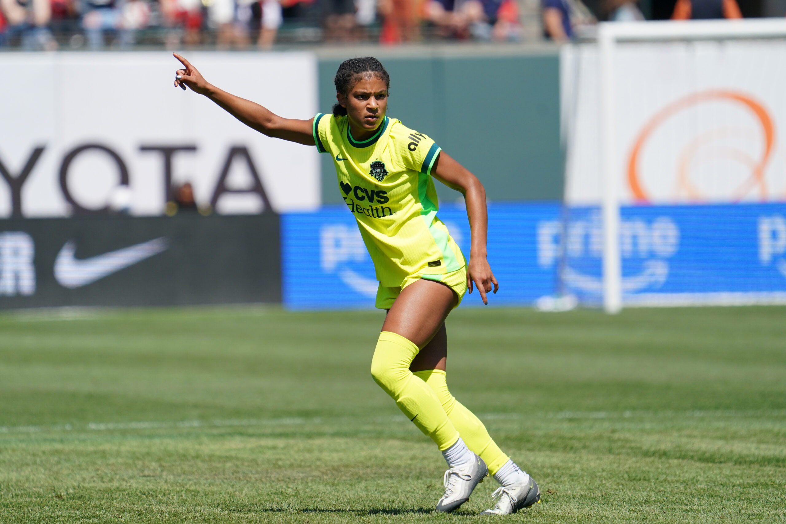 A player in a yellow uniform runs on the field and gestures to her right