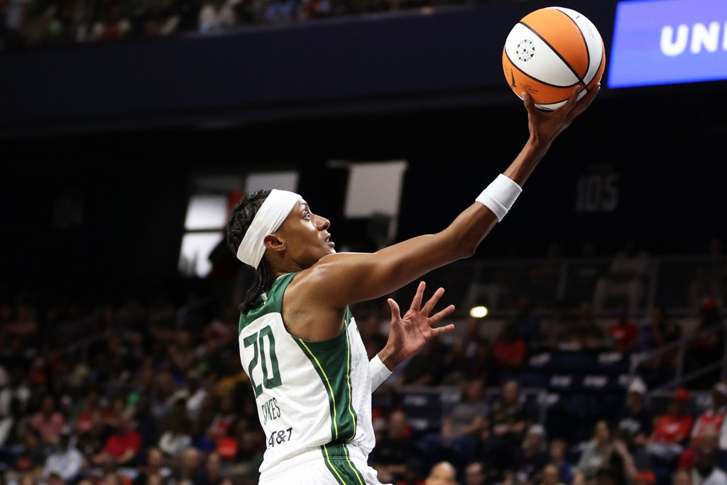 Brittney Sykes goes up for a layup, cradling the ball upward in her right hand while her eyes remain focused on the rim.