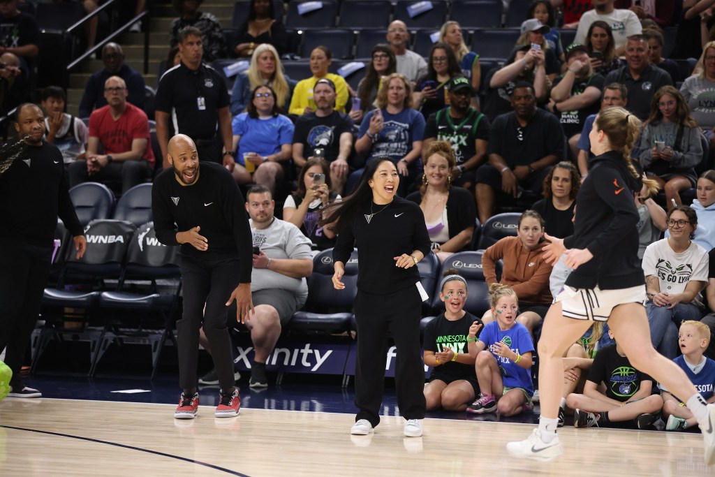 Golden State Valkyries head coach Natalie Nakase prepares to high-five guard Kate Martin. Nakase is smiling and shown from the front, while Martin is shown from the side. There is a large crowd in the background behind them.