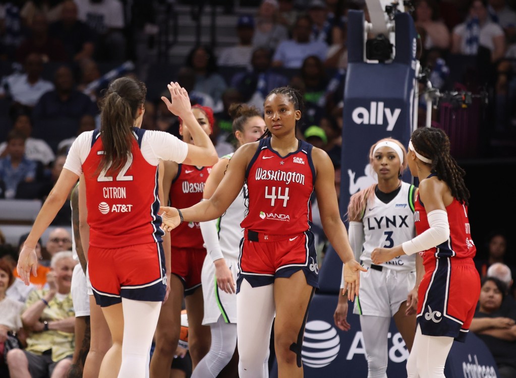 Washington Mystics guard Sonia Citron high-fives forward Kiki Iriafen. Citron is facing away from the camera; Iriafen is facing the camera and is expressionless as she extends her right hand.