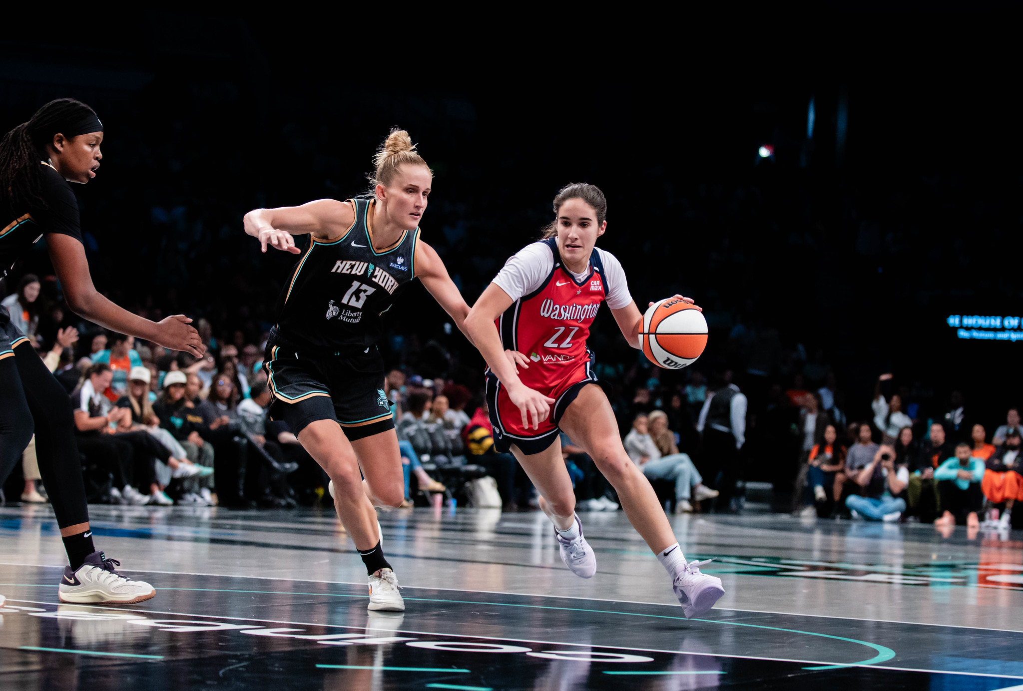 Photo of Washington's Sonia Citron driving toward the lane. New York's Leonie Fiebich is between her and the basket.
