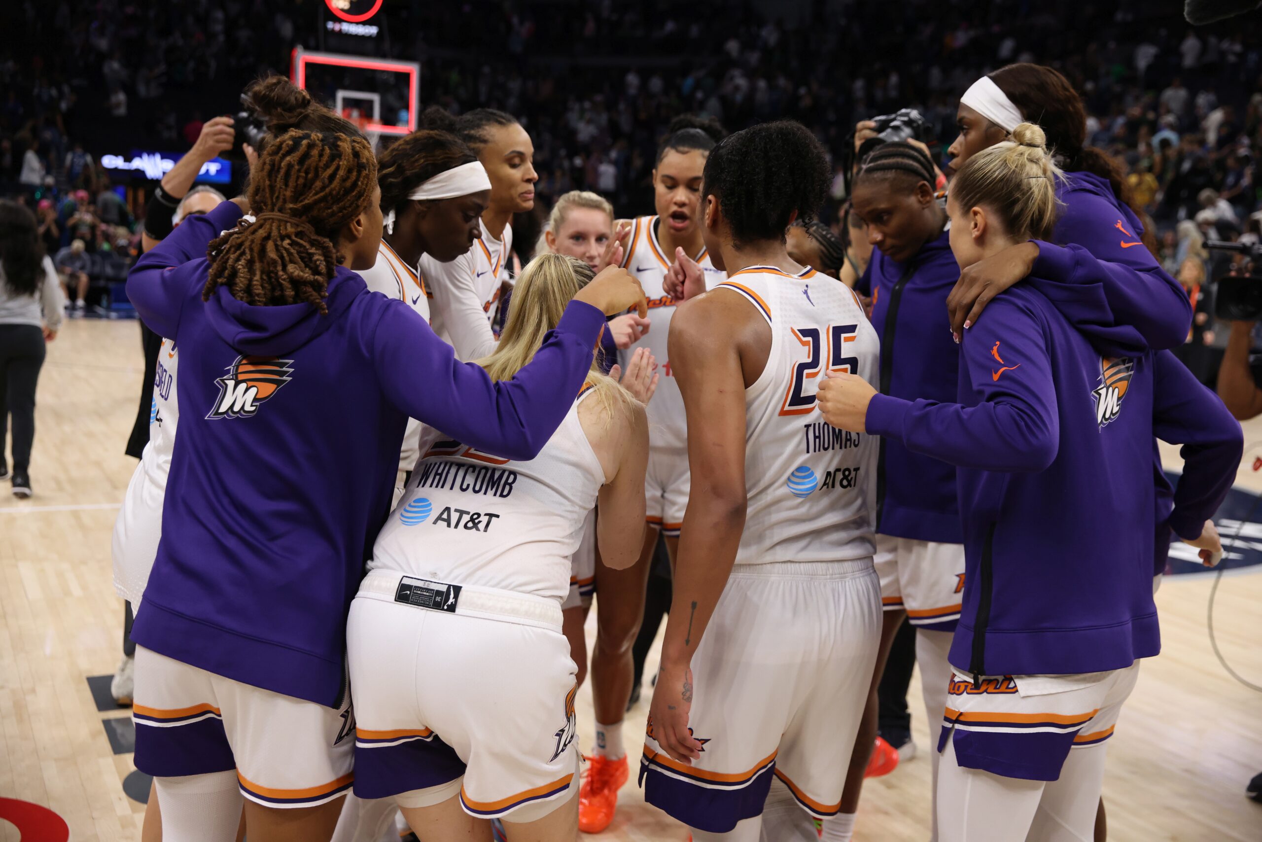 Phoenix players stand in a huddle after the final whistle. Most of them have their backs to the camera, but you can see Satou Sabally, DeWanna Bonner and Sami Whitcomb's faces on the other side.