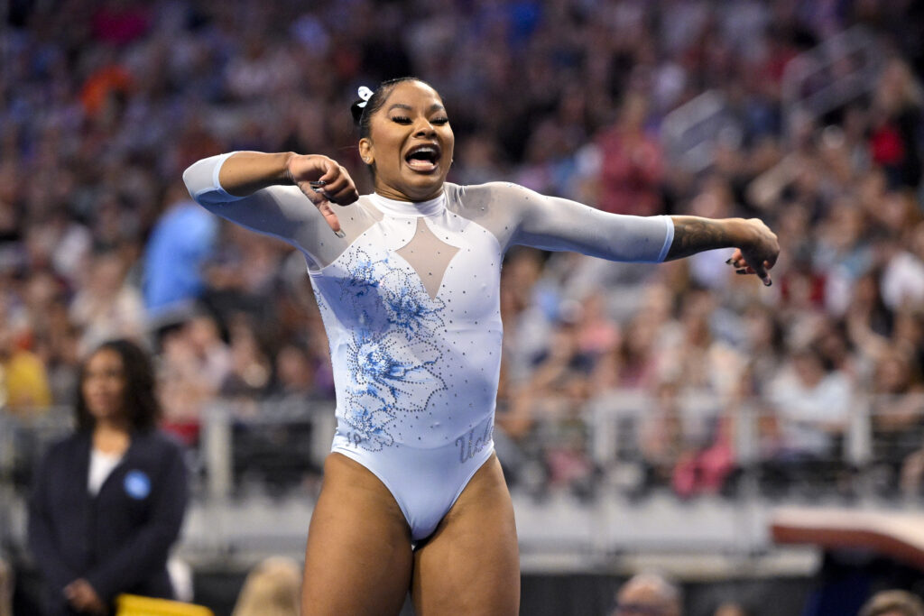 A gymnast in a white leotard dances as part of her floor routine.