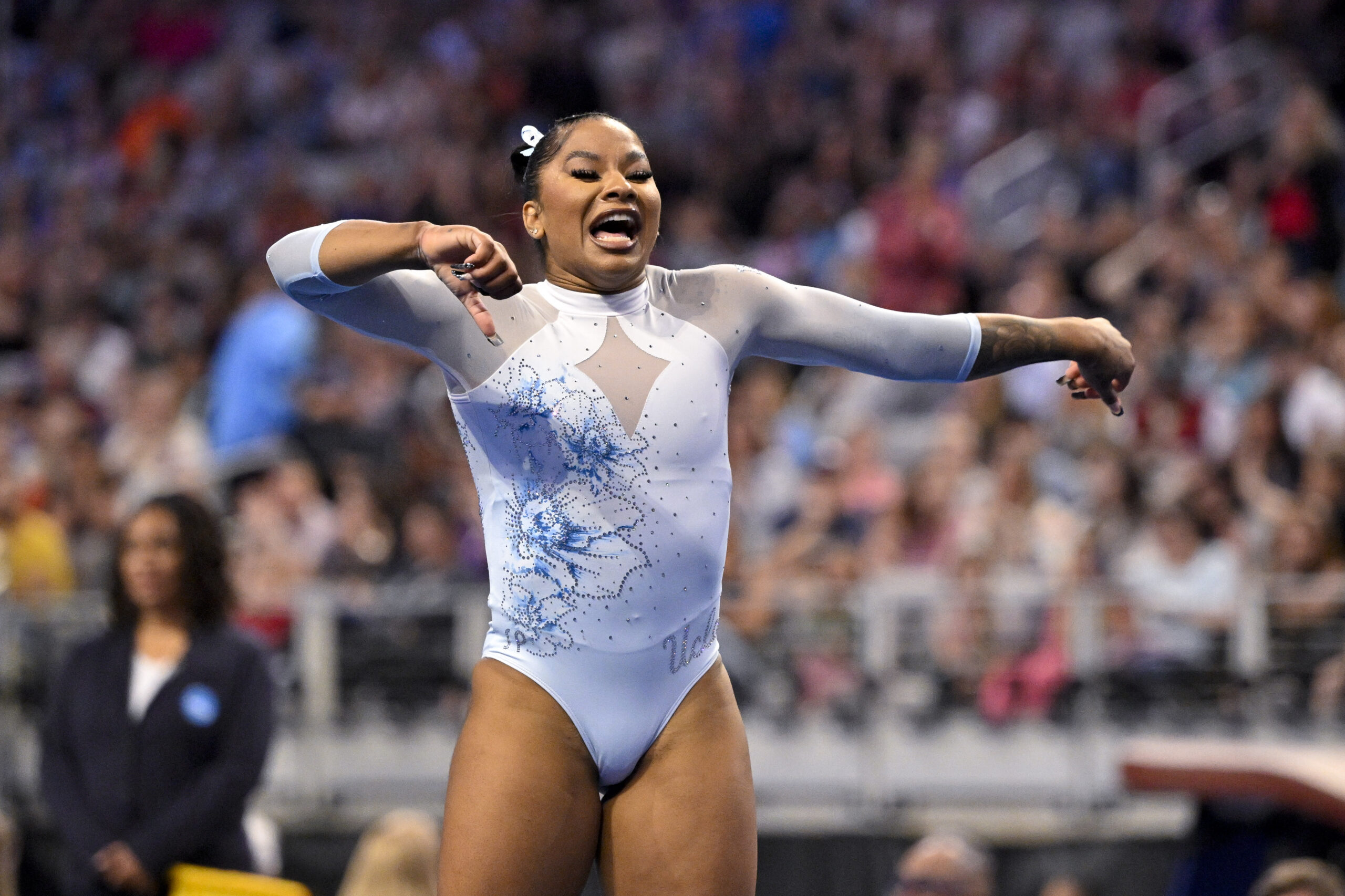 A gymnast in a white leotard dances as part of her floor routine.