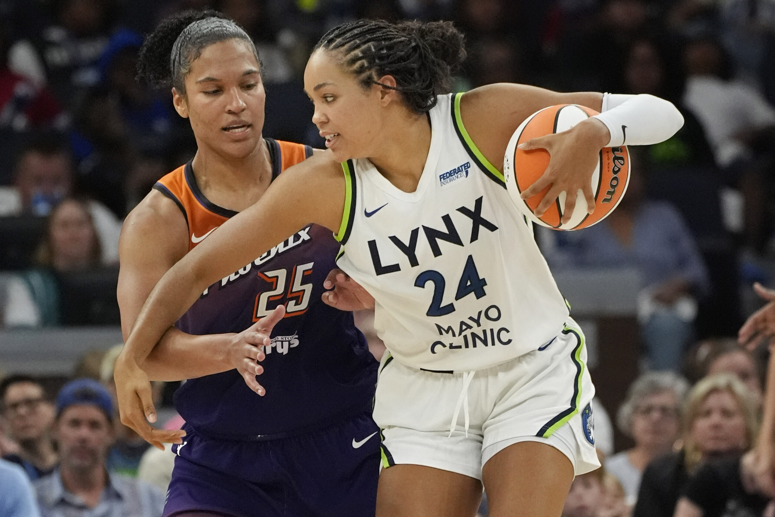 Minnesota Lynx forward Napheesa Collier dribbles the ball with her left hand as Phoenix Mercury forward Alyssa Thomas guards her tightly.