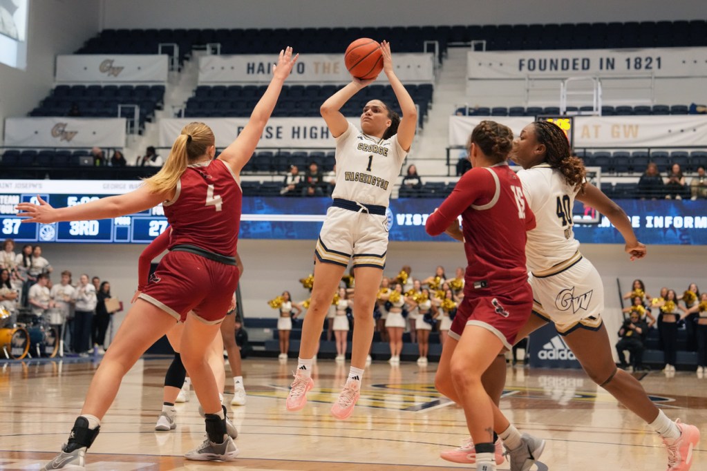 George Washington guard Gabby Reynolds shoots a right-handed fadeaway. Saint Josephโs forward Laura Ziegler reaches out with her right hand to try to contest the shot.