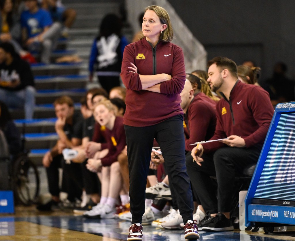 Minnesota head coach Dawn Plitzuweit stands on the sidelines with her arms folded across her chest during a Big Ten game.