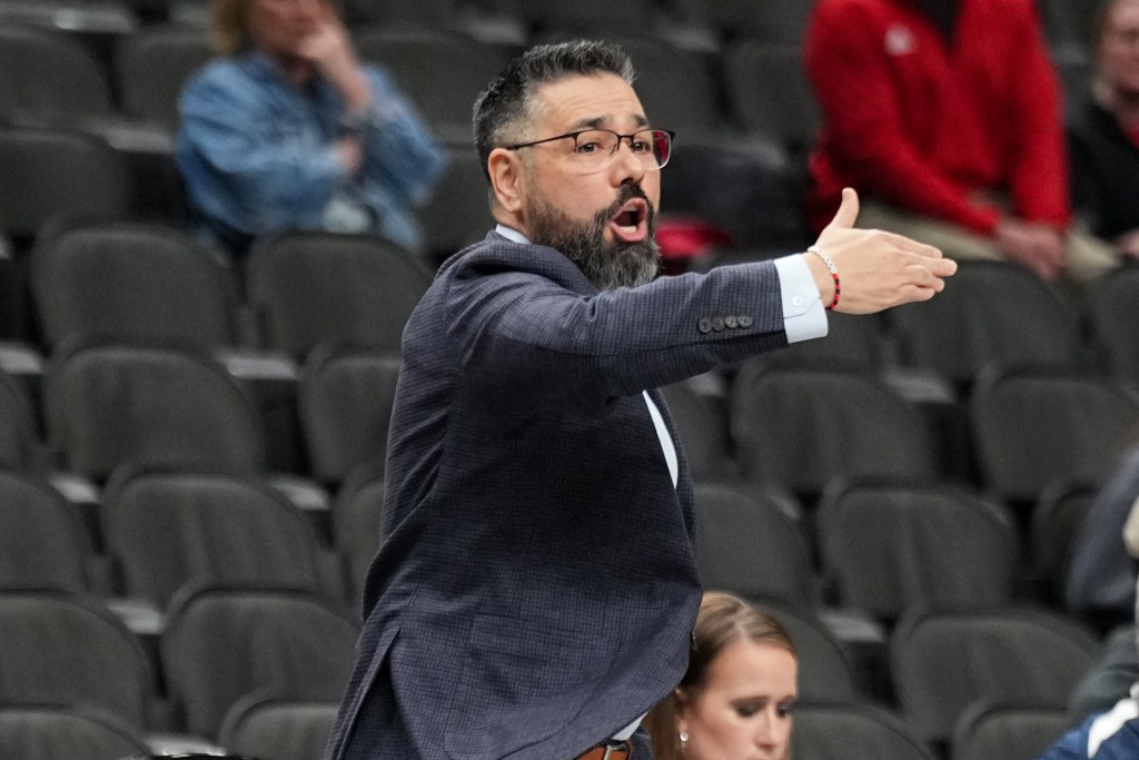 Utah head coach Gavin Petersen holds his right arm in front of his body, parallel to the floor, as he communicates with his team during a game.