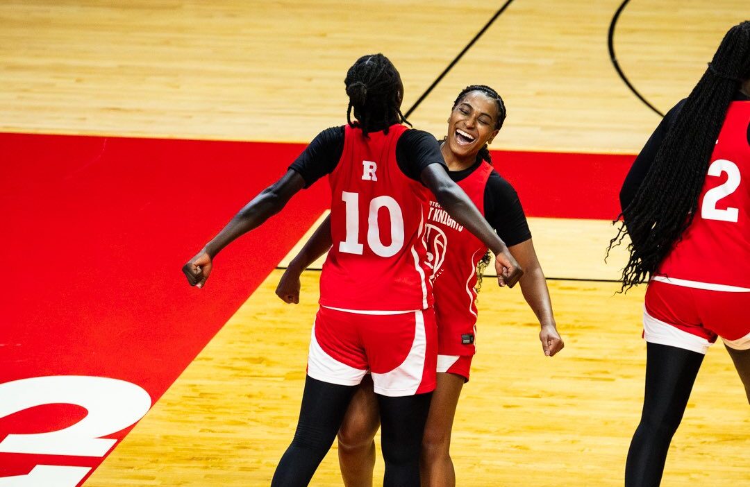 Basketball players chest bumping, wearing red practice jerseys.