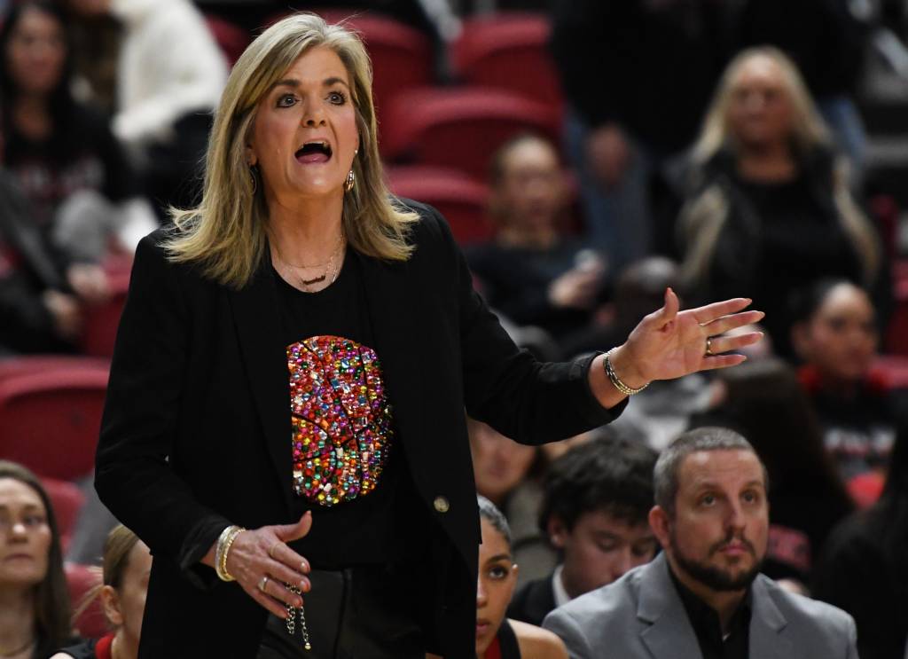 Texas Tech head coach Krista Gerlich shouts to her team during a game. Her left hand is extended away from her body, while her right hand is in front of her right hip.