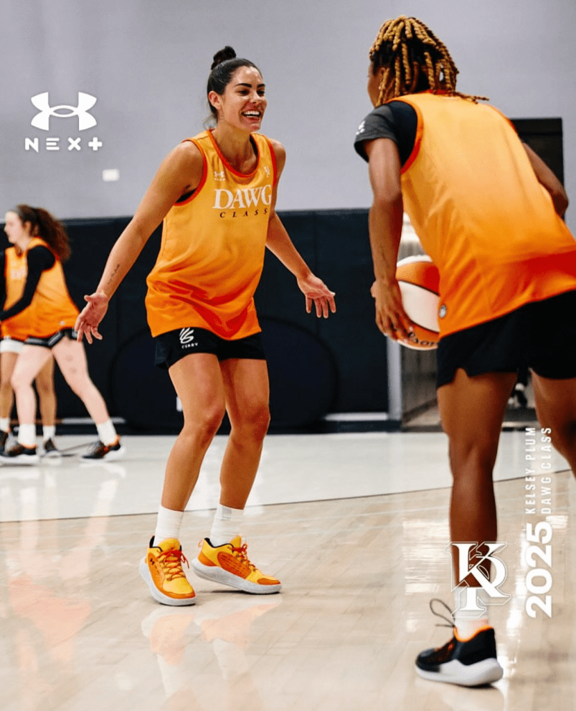 Two players face each other in basketball practice. Both are wearing orange tank tops that say Dawg Class. 