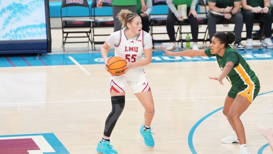 LMU forward Maya Hernandez holds the ball at the top of the key against San Francisco. She along with her defender are shown from the side.