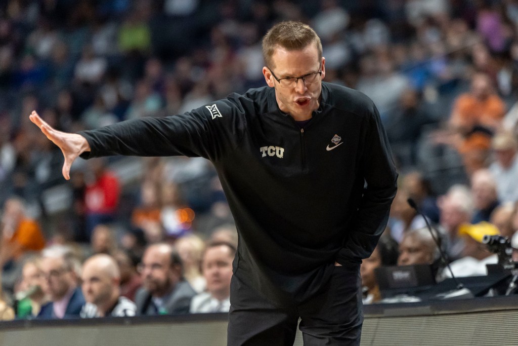 TCU head coach Mark Campbell extends his right arm straight out to the side and leans forward as he talks to someone on the sideline. The person he's addressing is not pictured.