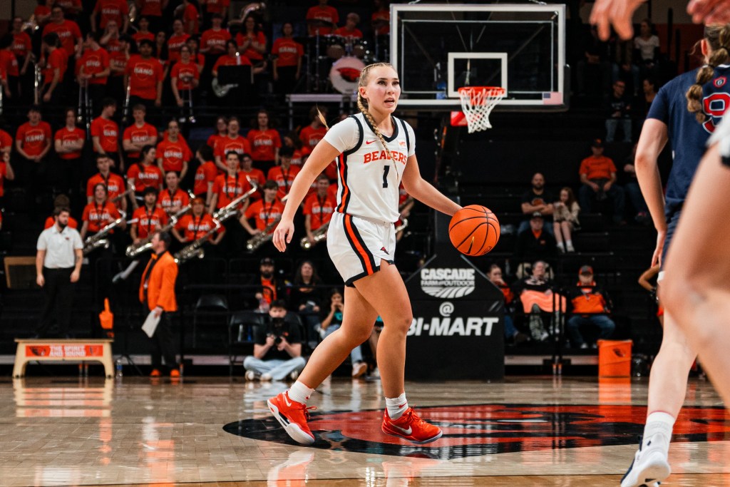 Oregon State guard Kennedie Shuler dribbles the basketball. She is shown from the front with an out of focus crowd behind her.