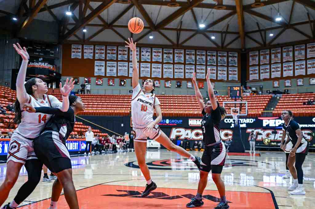 Pacific guard Sydney Ward shoots a floater from the middle of the paint. She is shown from the front with two defenders and a teammate around her.