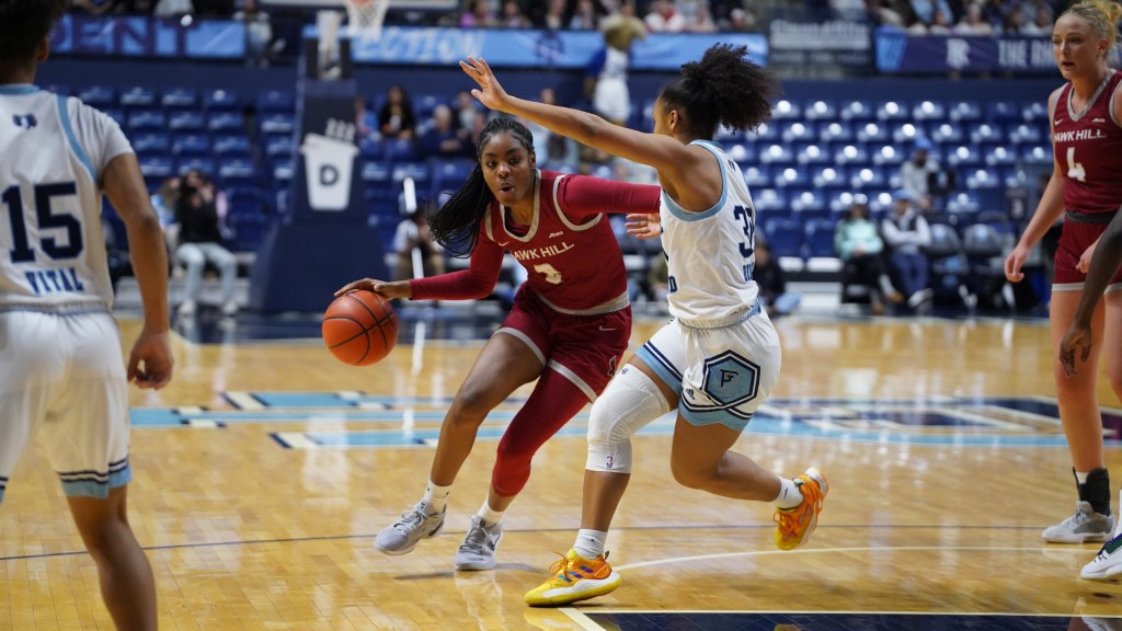Saint Josephโs guard Aleah Snead dribbles the ball with her right hand and stretches out her left arm to ward off Rhode Island guard Ines Debroise.