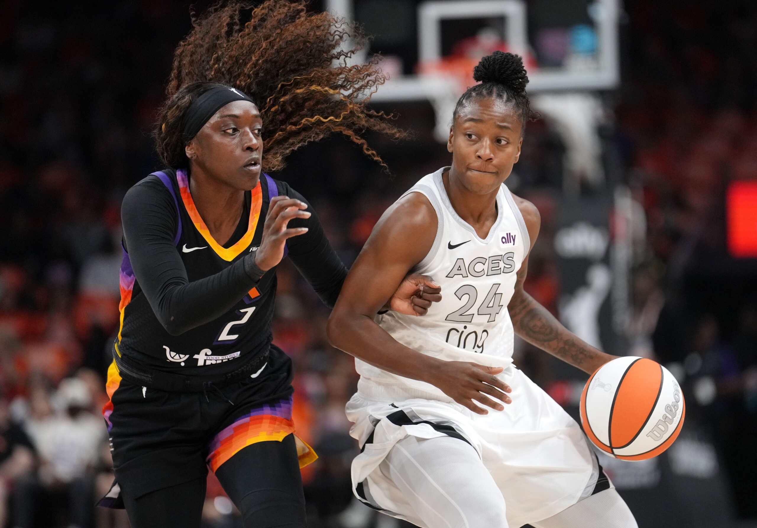 Two players battle for the ball. The player on the left is in a black uniform and the player on the right is in a white uniform.