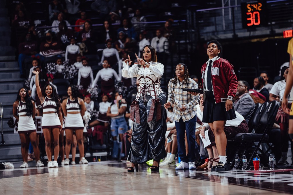 Alabama A&M head coach Dawn Thornton holds up signals with her fingers as players on the bench stand up.