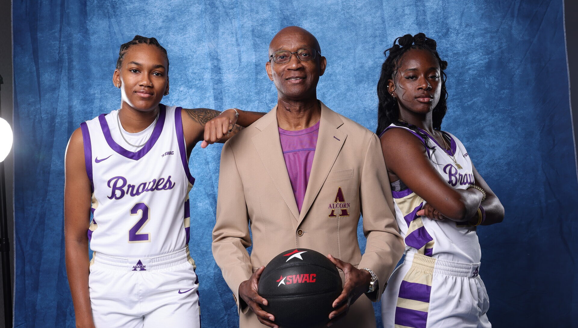 Alcorn State's Nakia Cheatham leans her arm on head coach Nate Kilbert's shoulder while Kiarra Henderson stands with her arms folded.