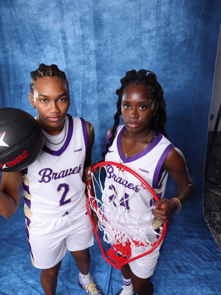 Nikea Cheatham holds a basketball while Kiarra Henderson holds a basketball during SWAC media day. They are both wearing white jerseys with purple stitching. 