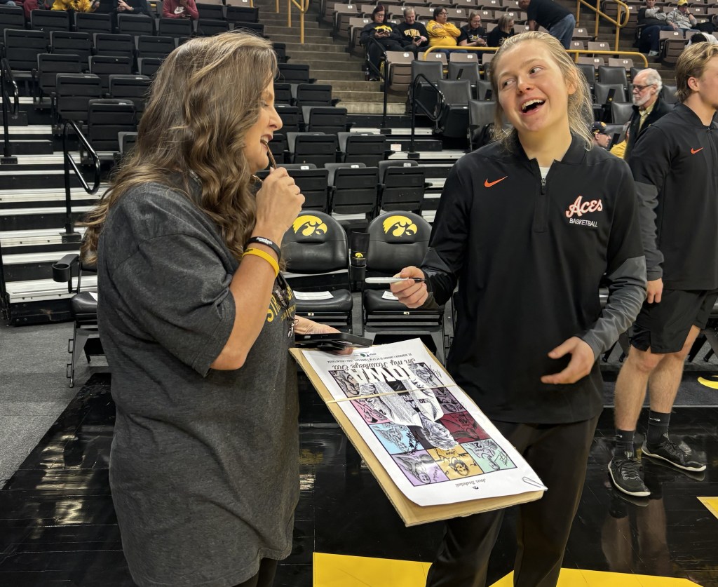 Former Iowa Hawkeye guard Molly Davis signs a poster for fan Traci Oleson on Nov. 9, 2025, in Iowa City, Iowa.