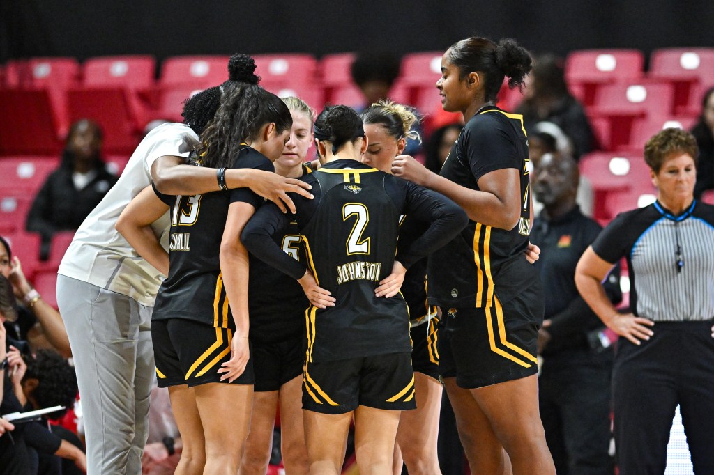 Towson women's basketball huddles during a game against Maryland.