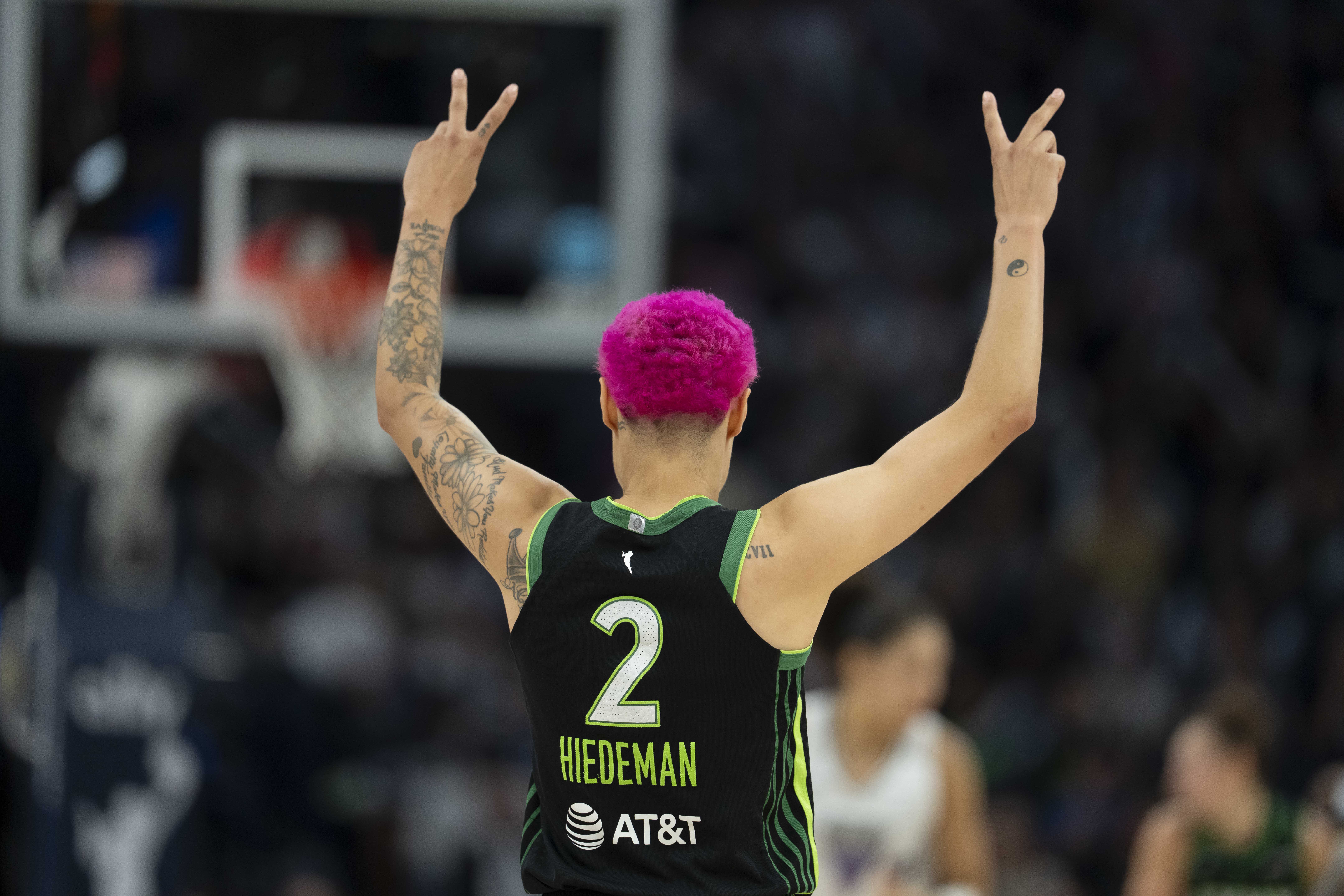 Natisha Hiedeman in her black No. 2 Lynx jersey holds up two fingers in both hands on either side of her bright pink hair.