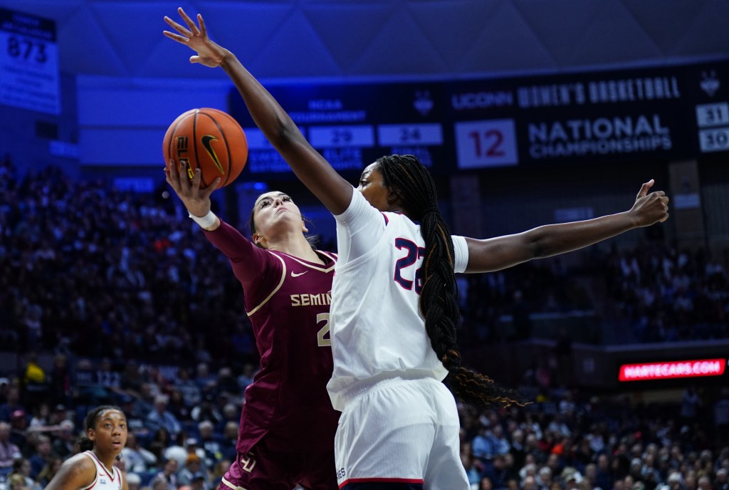 UConn forward Serah Williams uses her left hand to contest a shot from Florida State center Pania Davis. UConn guard KK Arnold looks on from several feet away.