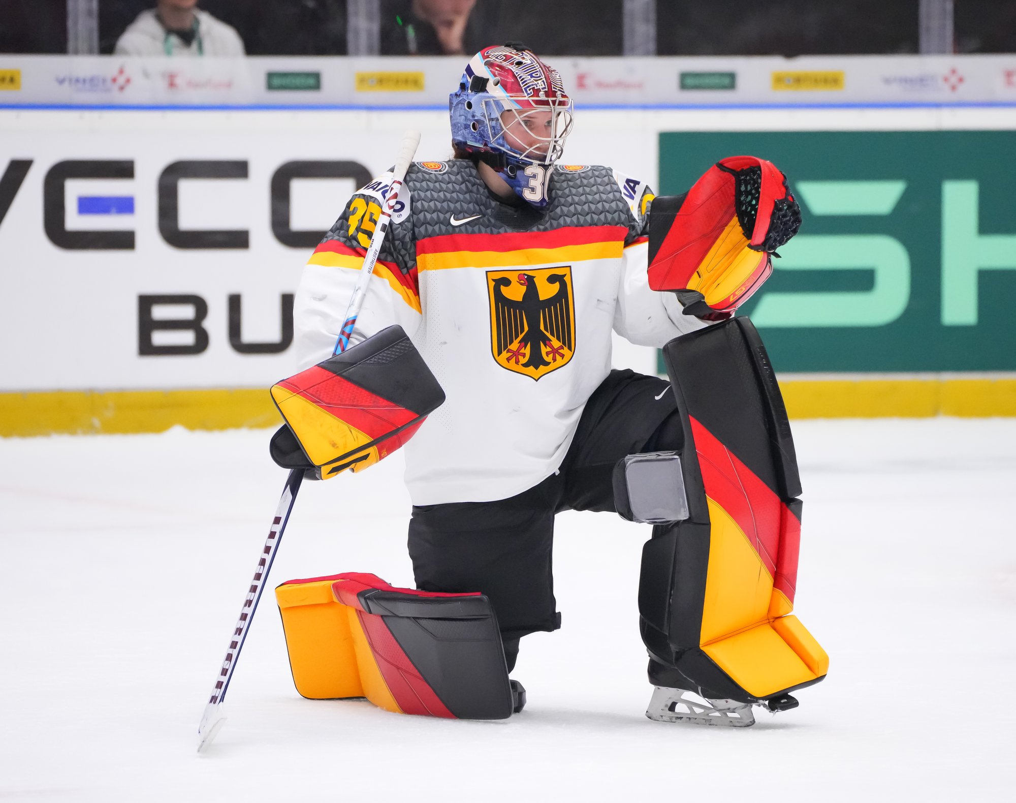 German goalkeeper Sandra Abstreiter kneels on the ice with her hockey stick upside down in her hand
