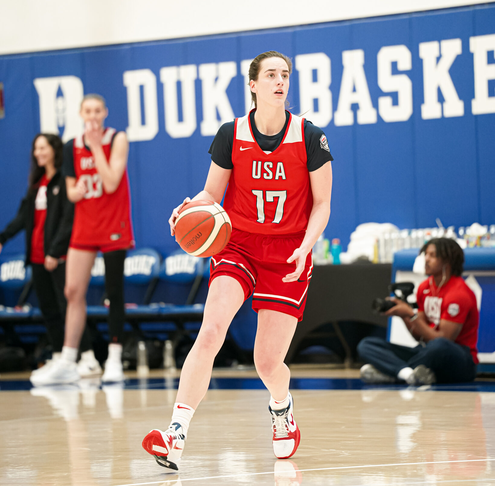Indiana Fever guard Caitlin Clark wears a red USA Basketball practice jersey and dribbles the ball during practice.